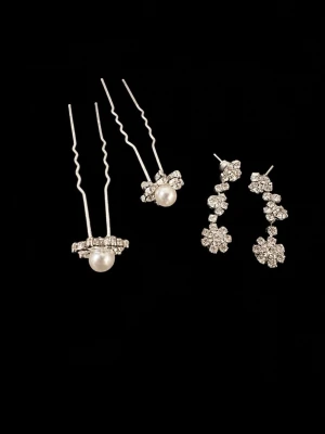 Glittriga örhängen med pärldetaljer - Säljer ett par silvriga örhängen med gnistrande stenar i blomform och ett par hårnålar med vita pärlor och strass. Perfekt för dig som gillar att sticka ut med accessoarer som glittrar och har eleganta detaljer.
