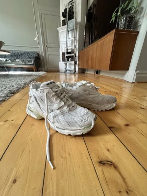 Vita Balenciaga Runners  - Säljer ett par vita Balenciaga Track sneakers med chunky sula och meshdetaljer. Skorna har flera lager av material, coola detaljer och Balenciaga-logga på plösen. Perfekta för dig som gillar statement sneakers och streetwear vibes.