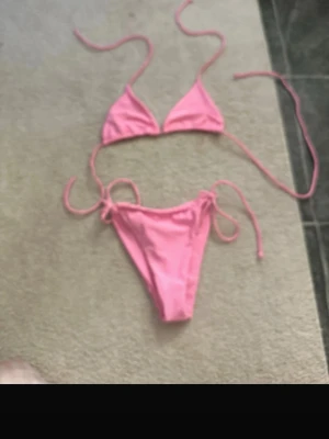 Rosa bikini med knyt i sidan - Söt rosa bikini med trekantsöverdel och knyt i sidan på både över- och underdel. Perfekt för lata dagar på stranden eller poolhäng. Klassisk modell som ger en snygg siluett och är enkel att justera för bästa passform.