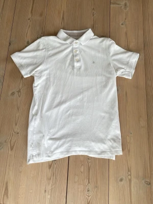 Vit pikétröja från Jack & Jones - Klassisk vit pikétröja från Jack & Jones med krage och tre knappar framtill. Tillverkad i mjuk bomull och har korta ärmar. Perfekt till en avslappnad och stilren look. 