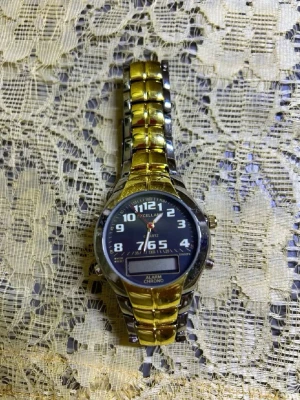 Guldig och silverfärgad klocka  - Stilren klocka  med både guld- och silverfärgad länk i metall. Svart urtavla med tydliga vita siffror och digital display. Klockan har klassisk rund form och metallarmband med spänne. Helt ny 