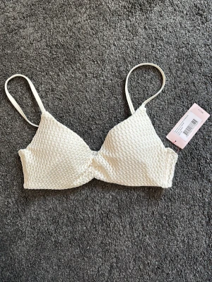 Vit bikiniöverdel 75D - Snygg vit bikiniöverdel från Nelly. Bikinin har en lätt vaddering och är helt oanvänd. 