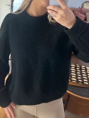 Rodebjer ocean melange stickad tröja  - Klassisk svart stickad tröja från Rodebjer med rund halsringning och ribbade muddar vid ärmslut och nederkant, modellen heter ”ocean melange”. Tröjan har en avslappnad passform och är tillverkad i ett mjukt, värmande material som passar perfekt till kyligare dagar. Nypris ca 2500kr.