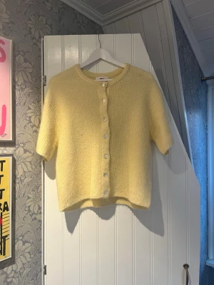 Gul kofta från Gina Tricot - Mysig gul kofta från Gina Tricot i ullblandning. Kort modell med rund halsringning, knappar framtill och halvlånga ärmar. Perfekt för lager-på-lager och ger en fräsch look till din outfit. Fint nu på våren eller till en kyligare sommardag! 💛HELT NY UTAN PRISLAPP!! 
