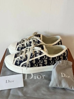 Dior Oblique låga sneakers - Snygga Dior Oblique sneakers i canvas med svart och vit monogramdesign. Skorna har vita snören, gummisula och klassisk låg profil. Perfekta för dig som gillar exklusiva och trendiga märken. Kommer med originalpåse och kort.