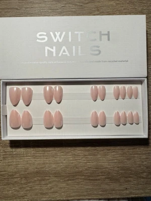 Switch Nails Maid Of Honor press-on - Snygga press-on naglar från Switch Nails i modellen Maid Of Honor. Naglarna har en kort mandelform och kommer i en naturligt ljusrosa nyans. Tillverkade av återvunnet material för en hållbar look. Perfekt för dig som vill ha salongskänsla hemma på nolltid. Säljs utan tillbehör.