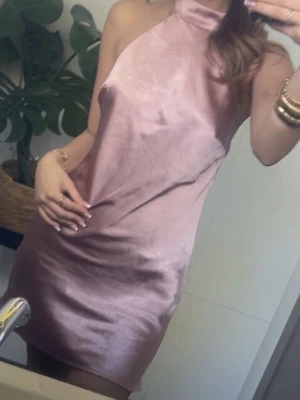 Rosa satin kortklänning - Säljer en snygg rosa kortklänning i satin med halterneck och ärmlös design. Använt en gång. Står storlek 32 men passar 34 och 36 