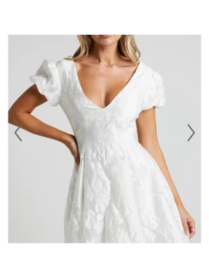 Vit klänning showpo  - Superfin vit klänning med v-ringad hals och korta puffärmar. Klänningen har ett blommönster i tyget. Perfekt till studenten och midsommar. Aldrig använd, med lappen kvar 🩷
