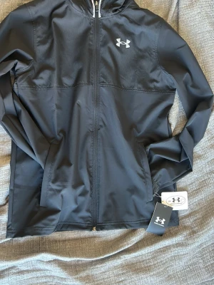 Underarmour vindjacka - Säljer denna riktigt fina vindjacka, aldrig använd med prislapp kvar!!😃 har helt enkelt inte kommit till användning🙂 skriv till mig vid intresse!🤝 tror att det står xl för barn men den sitter som en s vuxen 🙂