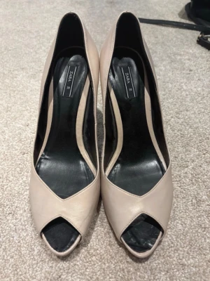 Beige peep toe pumps från Zara - Snygga beige pumps från Zara med peep toe och klassisk siluett. Skorna har en elegant klack och är tillverkade i ett slätt material med svart innersula. Perfekta för att lyfta vilken outfit som helst.