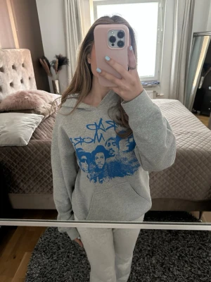Grå hoodie med blå Mount Rad More-print - Snygg grå hoodie med blått Mount Rad More-tryck framtill. Hoodien har huva och en stor magficka. Perfekt för en avslappnad och cool stil. Mjuk bomullskänsla och klassisk passform.