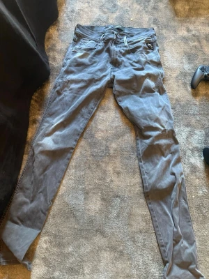 Grå slim fit jeans - Säljer ett par grå slim fit jeans med klassisk femficksdesign och dragkedjegylf. Jeansen har en tvättad look och är tillverkade i mjukt denimtyg med lite stretch för extra komfort. Perfekta för en avslappnad och trendig stil.