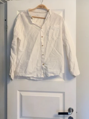 Vit klassisk skjorta med knappar - Vit skjorta i bomull med klassisk krage och bröstficka. Långärmad modell med knappar framtill och enkel, stilren design. Perfekt för en clean och tidlös look.