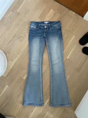 Bootcut jeans från Gina Tricot - Snygga bootcut jeans från Gina Tricot i ljusblå denim med klassisk femficksdesign. Jeansen har utsvängda ben och markerad tvätt längs låren för en cool vintagekänsla. Perfekta för dig som gillar retrostil och vill ha ett par bekväma jeans i bomull.