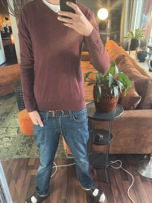 Vinröd V-ringad tröja - Vinröd långärmad tröja från Jack & Jones med V-ringning. Tröjan har en smal passform och är tillverkad i ett mjukt, tunt material som passar perfekt till jeans. Enkel och stilren design utan tryck eller mönster.