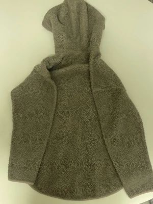 Beige teddyhoodie med halv dragkedja - Mysig beige hoodie i teddyfleece med huva och halv dragkedja framtill. Tröjan har lång ärm och rundad nederkant. Perfekt för dig som gillar en avslappnad och trendig stil.