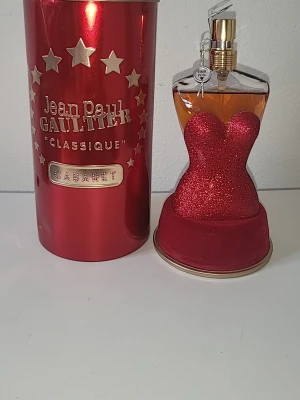 Jean Paul Gaultier Classique Cabaret - Jean Paul Gaultier Classique Cabaret Eau de Parfum i limiterad utgåva. Flaskan har en unik design i form av en kvinnokropp med rödglittrande klänning och guldfärgad kork. Kommer i en röd metallburk med stjärndetaljer och märkets logga.