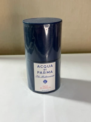 Acqua di Parma Fico di Amalfi parfym - Acqua di Parma Blu Mediterraneo Fico di Amalfi är en elegant parfym i en mörkblå, cylinderformad förpackning. Doften är inspirerad av Medelhavet och levereras i en exklusiv kartong med vita och blå detaljer. Perfekt för dig som gillar fräscha och lyxiga dofter.
