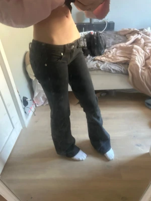 Svarta bootcut jeans med låg midja - Snygga svarta bootcut jeans med låg midja och klassiska fem fickor. Jeansen har en stilren look med silverfärgade knappar. Perfekta för dig som gillar en trendig och avslappnad stil. Något mindre slitning längs ner vid foten men inget som märks. De är perfekt längd för mig som är 167cm lång! Pris kan diskuteras❣️