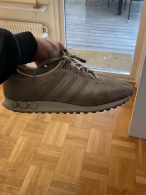 Adidas la trainer  - Snygga beige sneakers från Adidas med klassiska tre ränder på sidan. Ovandelen är i meshmaterial för bra andningsförmåga och sulan har rundade gummidetaljer för extra grepp. Perfekta för en sportig och stilren look.  Sulan är rätt sliten och nya skosnören behövs 