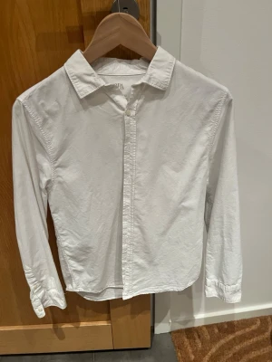Vit skjorta från Zara, stl 152/12 y - Klassisk vit skjorta från Zara i bomull med lång ärm och knappar framtill. Skjortan har en stilren design med krage och passar perfekt till många olika outfits. Mycket fint begagnat skick, knappt använd, superfin till skolavslutningen🥳💙! 