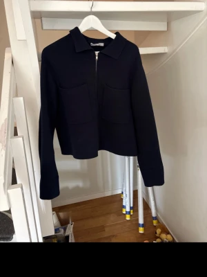 Mörk blå overshirt med dragkedja - Stilren mörkblå overshirt med krage och två stora fickor framtill. Jackan har lång ärm och stängs med dragkedja. Perfekt för lager-på-lager och enkel att matcha till olika outfits.