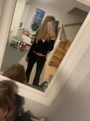Svart omlottopp med knyt - Snygg svart omlottopp med lång ärm och knyt i midjan. Toppen är croppad och har en djup v-ringning som ger en trendig look. 