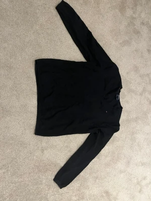 Svart långärmad tröja Tommy Hilfiger - Klassisk svart långärmad tröja från Tommy Hilfiger i mjuk pima cotton blend. Tröjan har rund halsringning och en liten diskret logga på bröstet. Perfekt för en stilren och enkel look.
