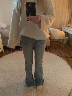 Ljusblå bootcut jeans - Säljer ett par ljusblå bootcut jeans med klassisk femficksdesign och låg midja. Jeansen har en avslappnad passform över låren och lätt utsvängda ben. Perfekta till en casual look och passar till det mesta i garderoben. Helt nya. På nellys hemsida kostar de 700kr