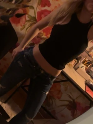 Svart croppad ribbad linnetopp - Säljer en svart croppad linnetopp med ribbad struktur. Toppen är ärmlös och har en tight passform som framhäver midjan. Perfekt att matcha med jeans eller kjol för en trendig look.