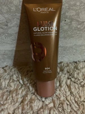 L'Oréal Lumi Glotion 904 Deep Glow TIKTOK TREND - L'Oréal Lumi Glotion i nyansen 904 Deep Glow är en flytande highlighter som ger naturlig lyster till huden. Kommer i en brun tub med roséguldfärgad text och lock. Perfekt för att boosta glow och highlighta ansiktet med en varm, gyllene ton.