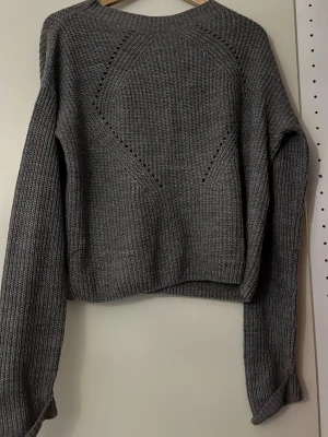 Grå stickad tröja med mönster - Snygg grå stickad tröja med diskret hålmönster. Liten i storleken.