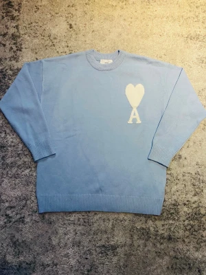 Ljusblå Ami Paris tröja - Riktigt fet Ami tröja i ljusblå med vit logga på bröstet. Tröjan är storlek S och skicket är mycket bra, utan  några defekter. Perfekt för dig som söker en stilren look med en gnutta elegans. Hör gärna av dig om funderingar som mått, pris, bilder etc. Så löser vi! 😁