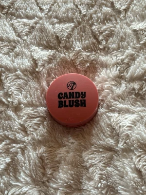 W7 Candy Blush rouge i rosa - Söt rund dosa med W7 Candy Blush i färgen Galactic. Rouget har en härlig rosa ton och kommer i en kompakt plastförpackning som är lätt att ta med i väskan. Perfekt för att ge kinderna en fräsch och ungdomlig look.