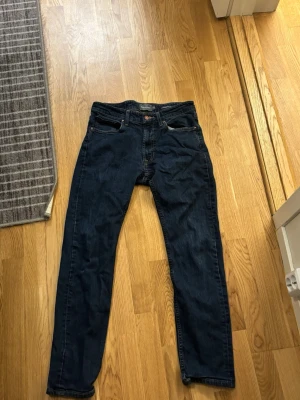 Mörkblå raka jeans - Säljer ett par mörkblå jeans med rak passform och klassisk femficksdesign. Jeansen har normal midja och är tillverkade i denim. Perfekta för dig som gillar en enkel och tidlös stil.