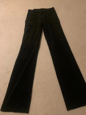 Svarta juicy cutore byxor  - Säljer ett par svarta manchesterbyxor med vida ben och stora fickor både fram och bak. Byxorna har en klassisk look med knappdetaljer på bakfickorna och är perfekta för dig som gillar retrostil och sköna material.