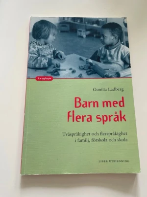 Barn med flera språk kursbok - Kurslitteratur: 'Barn med flera språk' av Gunilla Ladberg. Boken har grön framsida med röd text och svartvit bild på barn. Innehåller fakta om tvåspråkighet och flerspråkighet i familj, förskola och skola. Mjukt omslag, svensk text. Kan finnas enstaka markering. Säljes till angivet pris eller prisförslag.