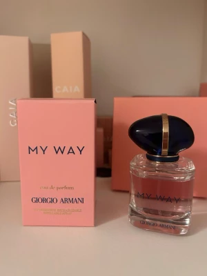 My Way parfym från Giorgio Armani - Säljer en elegant parfym, My Way från Giorgio Armani. Flaskan är genomskinlig med en mörkblå, oval kork och gulddetalj. Doften kommer i en stilren rosa kartong med blå text. Perfekt för dig som gillar exklusiva och fräscha dofter. 30ml flaska. 