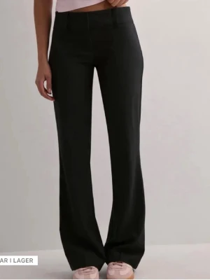 Svarta lågmidjadee kostymbyxor  - Svarta lågmidjade kostymbyxor från Nelly, använd fåtal gånger då de va lite för stora så de är som nya💕