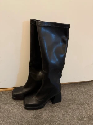 Svarta höga boots - Snygga svarta stövlar i glansigt skinnimitation. Klackhöjd : 9cm