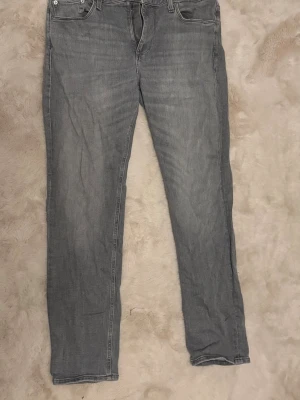 Grå jeans Jack & Jones - Snygga grå jeans med klassisk femficksmodell och raka ben. Jeansen har normal hög midja. Tillverkade i denim med synliga sömmar och silverfärgade nitar. Perfekta för en casual stil.