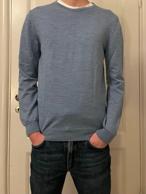 Ljusblå tröja från Stenströms - En stilren ljusblå tröja med rund halsringning och långa ärmar. Tröjan har ribbade muddar vid ärmslut och nederkant, vilket ger en snygg passform. Perfekt att matcha med jeans för en clean look.