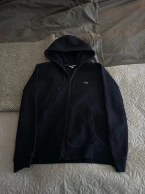 Mörkblå hoodie från Lacoste - Mörkblå Lacoste zip hoodie, storlek XL passar L bra. Priset är diskuterbart