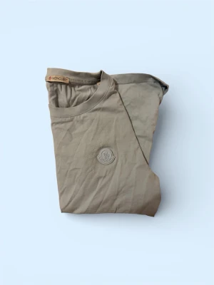 Baby Blue  t-shirt från Moncler - Snygg ljusblå t-shirt från Moncler med diskret broderad logga på bröstet. Klassisk rund halsringning och korta ärmar. Tillverkad i mjuk bomull som känns skön mot huden. Perfekt för en clean och stilren look.