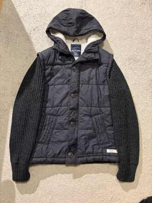 Cardiganjacka Angelo Litrico - Snygg mörkblå cardiganjacka från Angelo Litrico med stickade svarta ärmar och teddyfoder i huvan.🙌 Västen har både knappar och dragkedja✅ Hör av dig om du har minsta fråga eller om du vill diskutera pris🤝