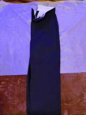 Svarta Jenas från Dickies - Snygga Svarta byxor från Dickies med raka ben och klassisk passform. Byxorna har två bakfickor med knapp och bälteshällor. Perfekta för en clean och stilren look. Materialet är slitstarkt och bekvämt, typiskt för Dickies.