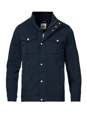 J.lindeberg field jacket oanvänd - Stilren mörkblå vindjacka från J.Lindeberg med fyra framfickor med lock och tryckknappar. Jackan har hög krage, dragkedja och knappslå framtill. Perfekt för blåsiga dagar och enkel att matcha till olika outfits. Nypris 3500kr.