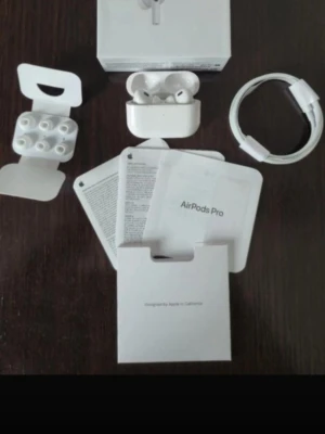 Apple AirPods Pro trådlösa hörlurar - Säljer ett par vita Apple AirPods Pro med laddningsetui, extra silikonpluggar och laddkabel. Hörlurarna har en stilren design i blank plast och levereras med originalförpackning och manualer. Perfekta för dig som vill ha grymt ljud och smidig anslutning.