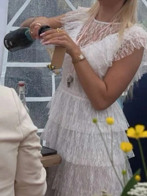 Vit spetsklänning från Bubbleroom - Supersöt vit spetsklänning från Bubbleroom med volangdetaljer och flera lager. Klänningen har v-ringad spets upptill, kort ärm med volang och knappar i ryggen. Perfekt för sommarens alla tillfällen! Studentklänning som endast är använd 1 gång