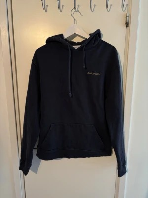Axel Arigato hoodie - Snygg mörkblå hoodie från Axel Arigato med broderad text på bröstet. Klassisk känguruficka framtill, justerbar huva med dragsko och mjukt material som känns skönt mot huden. Perfekt för en avslappnad och trendig look.